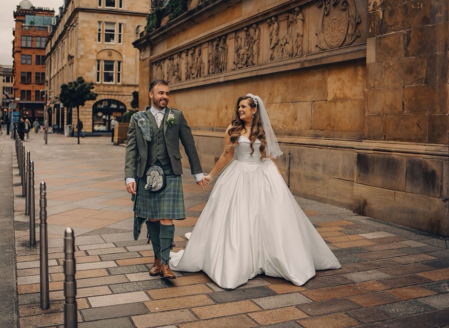 Bride and groom walking outside holding hands