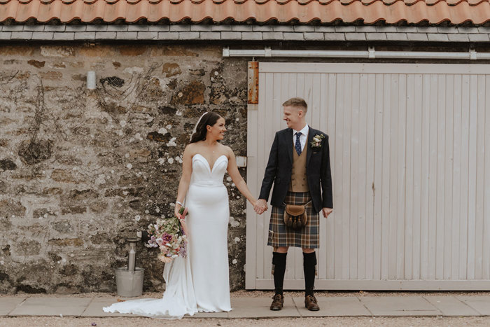 bride and groom stand with falside mill in background