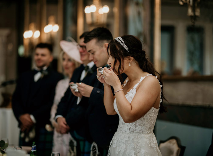 Bride in focus as she drinks from a quaich