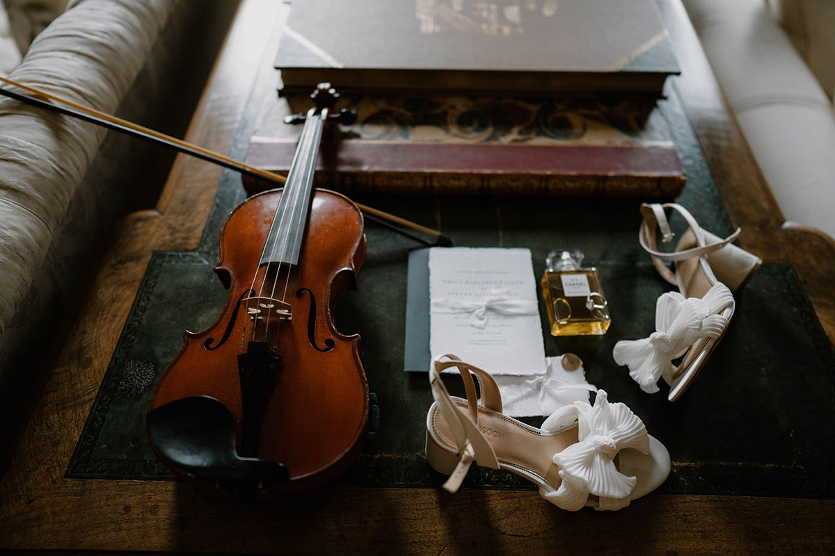 Wedding flat lay featuring a violin, bridal shoes and stationery at Cluny Castle in Aberdeenshire.