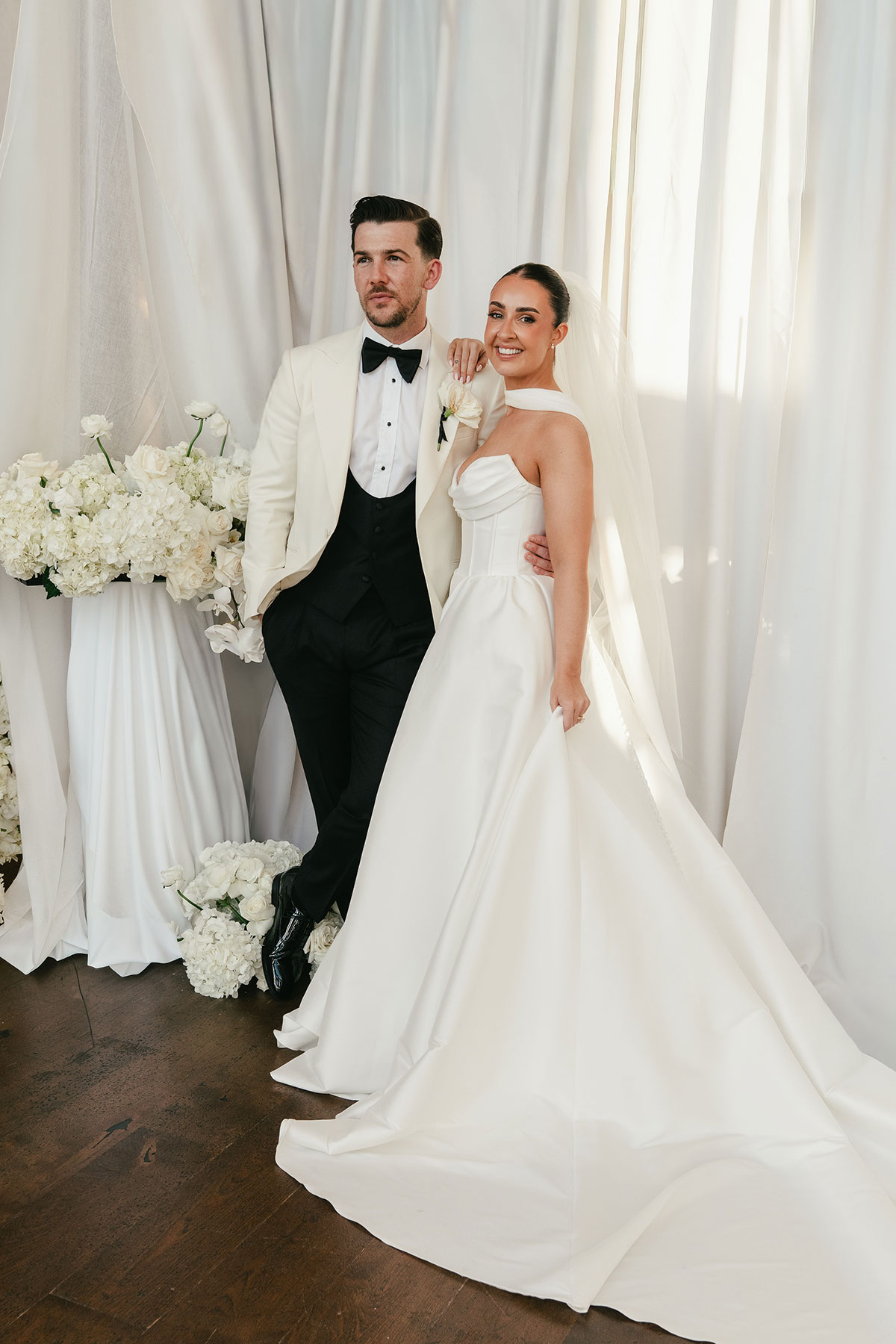 Elegant bride and groom portrait with white floral styling and draped backdrop at Enterkine Country House wedding