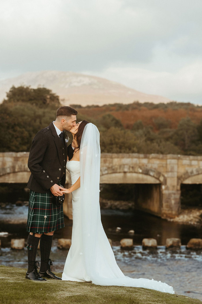 bride and groom kiss outdoors next to dougarie boathouse stepping stones