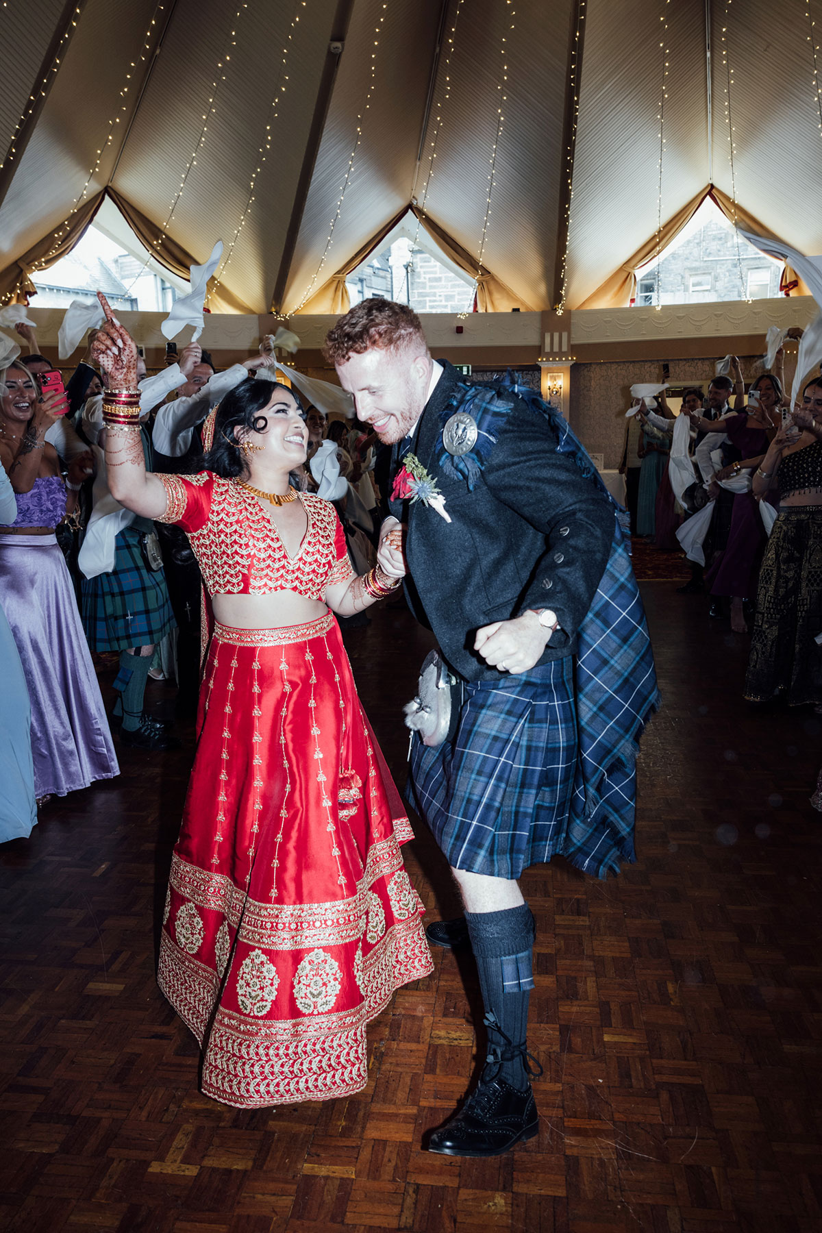 wedding guests waving napkins during an energetic reception celebration beneath fairy lights at Atholl Palace Hotel
