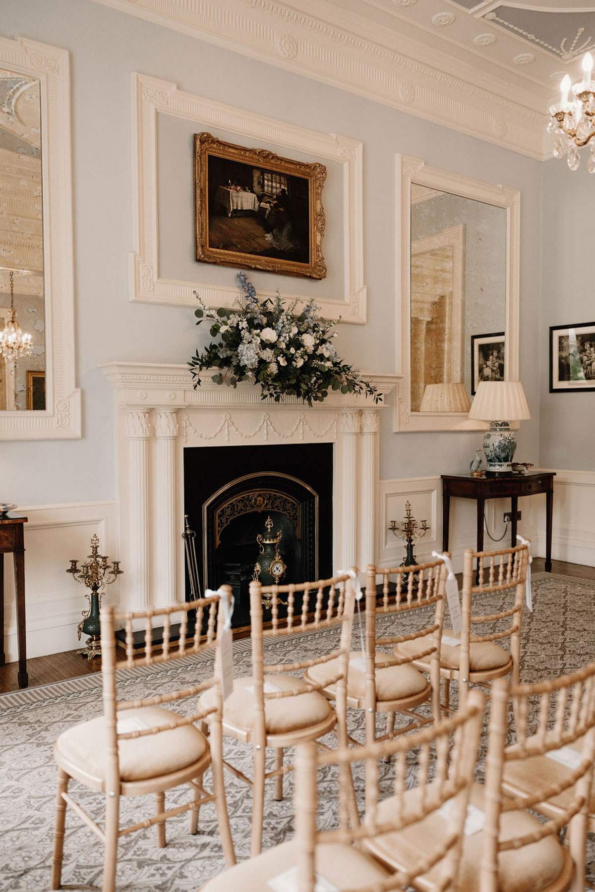 Elegant wedding ceremony room at Crossbasket Castle with Chiavari chairs, fireplace and floral arrangement