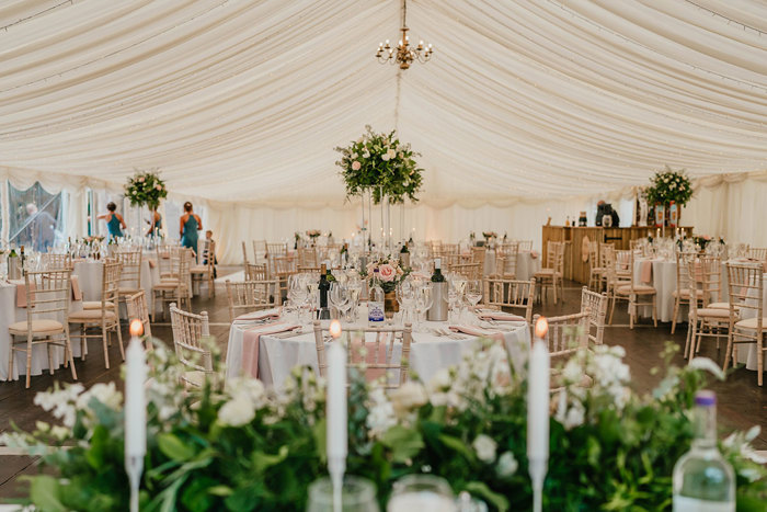 The inside of a marquee set up with tables and chairs for a wedding 