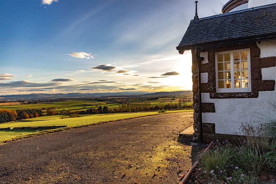 the corner of a building and views over hills at sunset