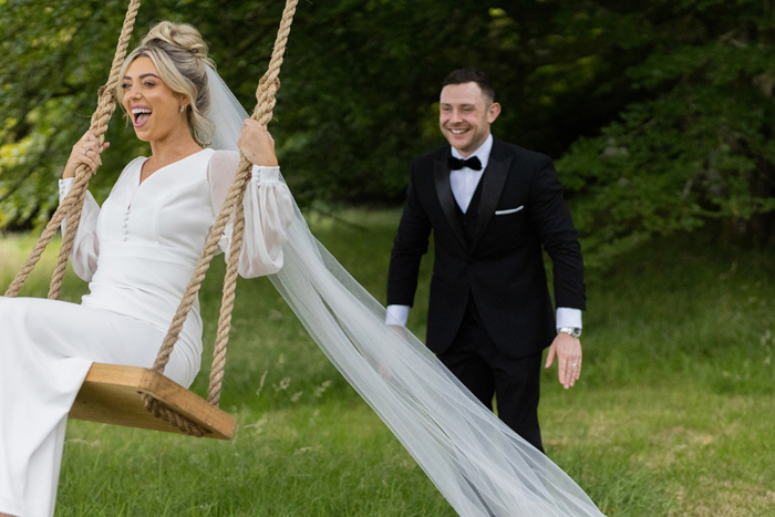 Groom pushes bride on a swing