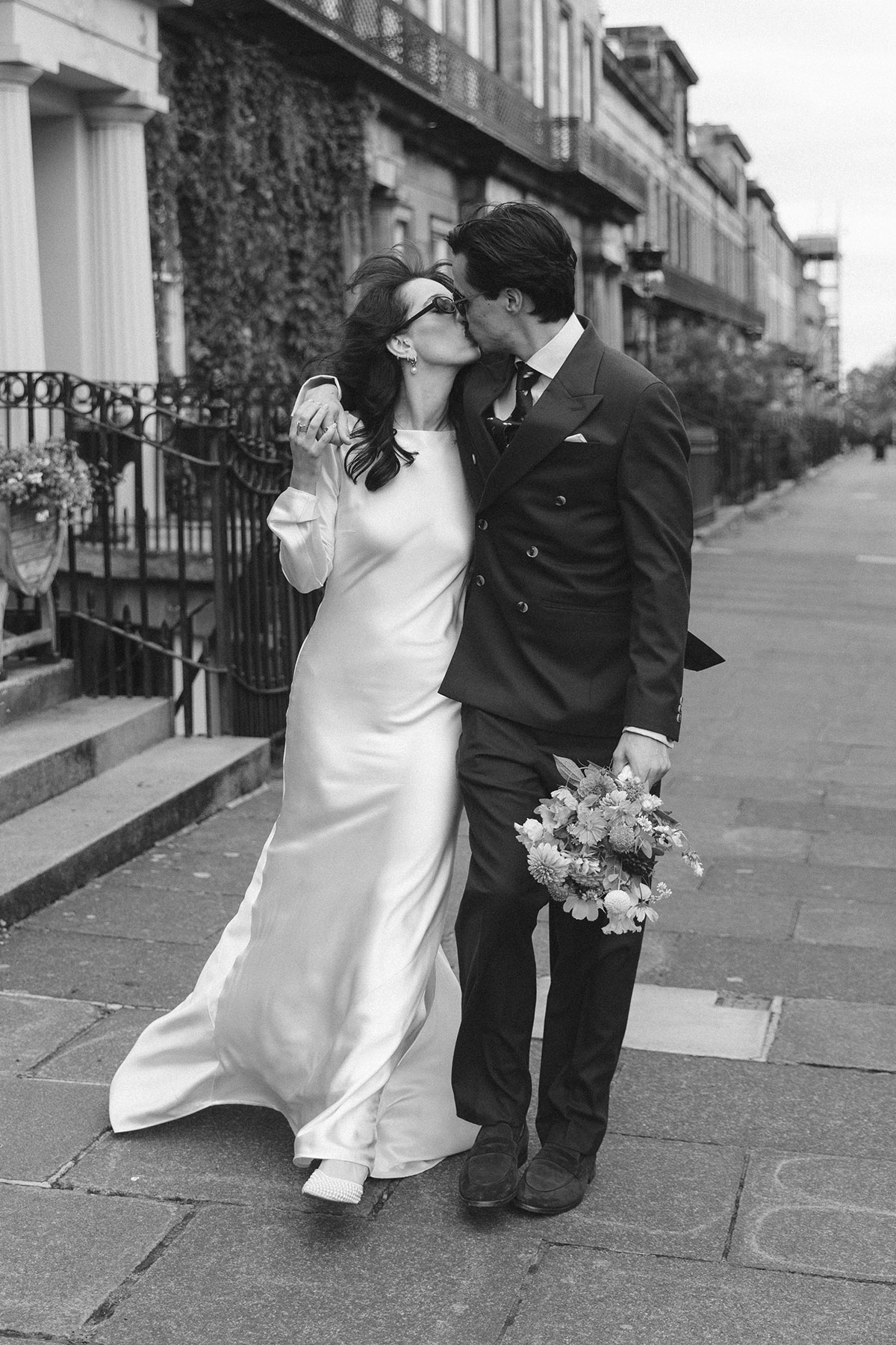 Bride and groom kissing on an Edinburgh street after their intimate city wedding