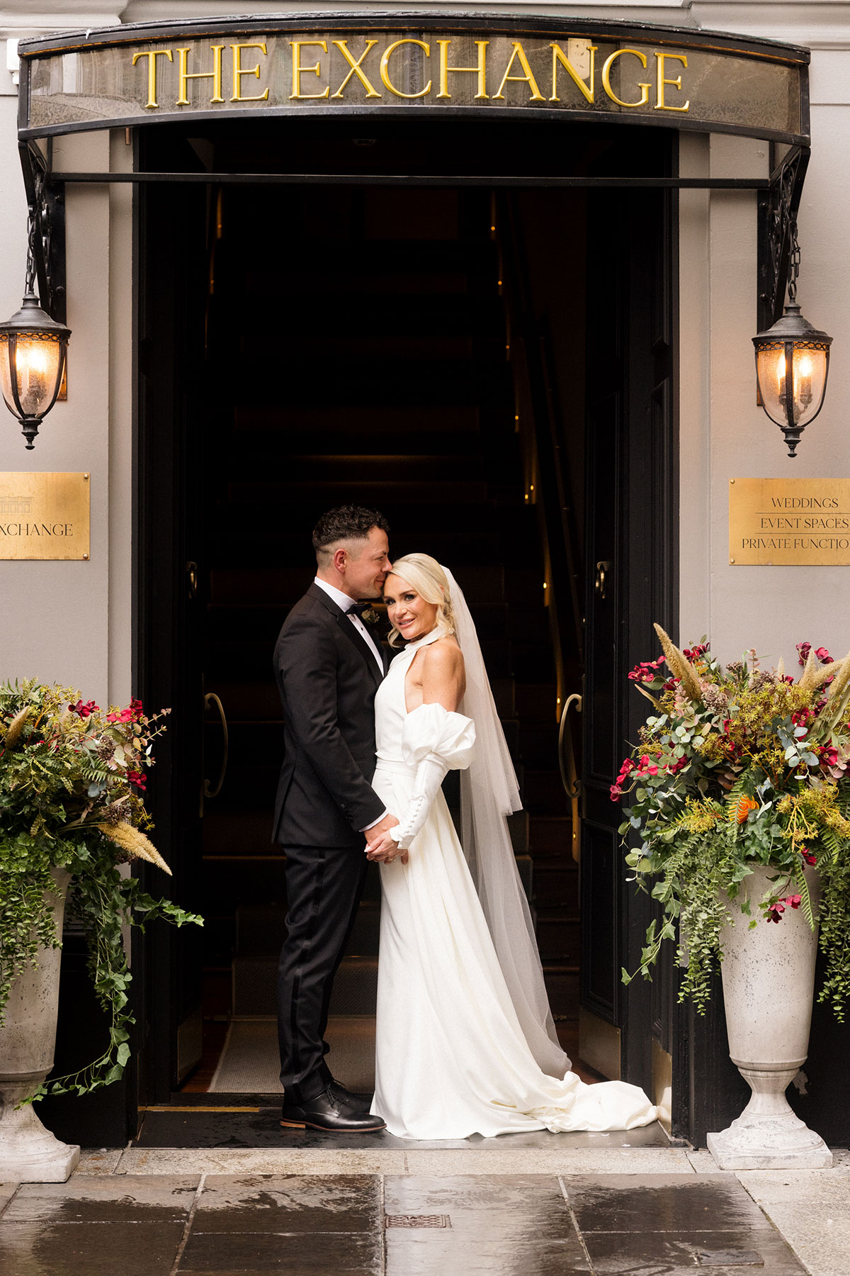 Bride and groom posing outside The Exchange wedding venue in Glasgow city centre beneath the venue entrance