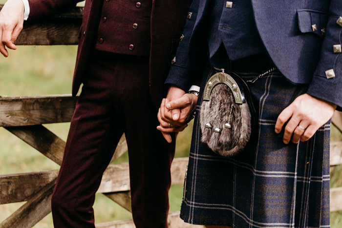 Close up image of grooms holding hands