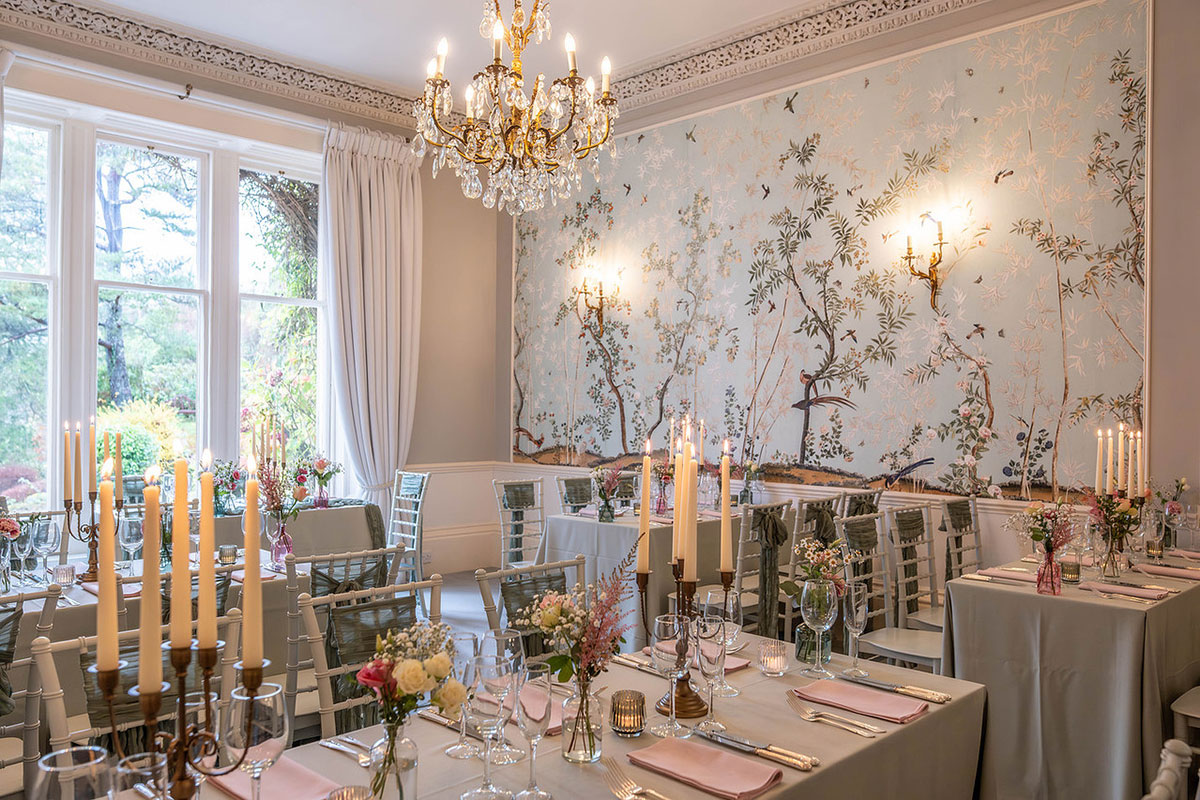 Candlelit indoor wedding reception with round tables, gold-rimmed glassware and floral centrepieces