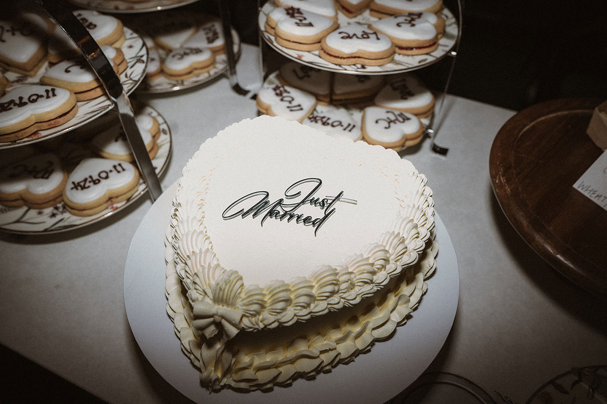 A white heart shaped cake with heart shaped iced biscuits next to it