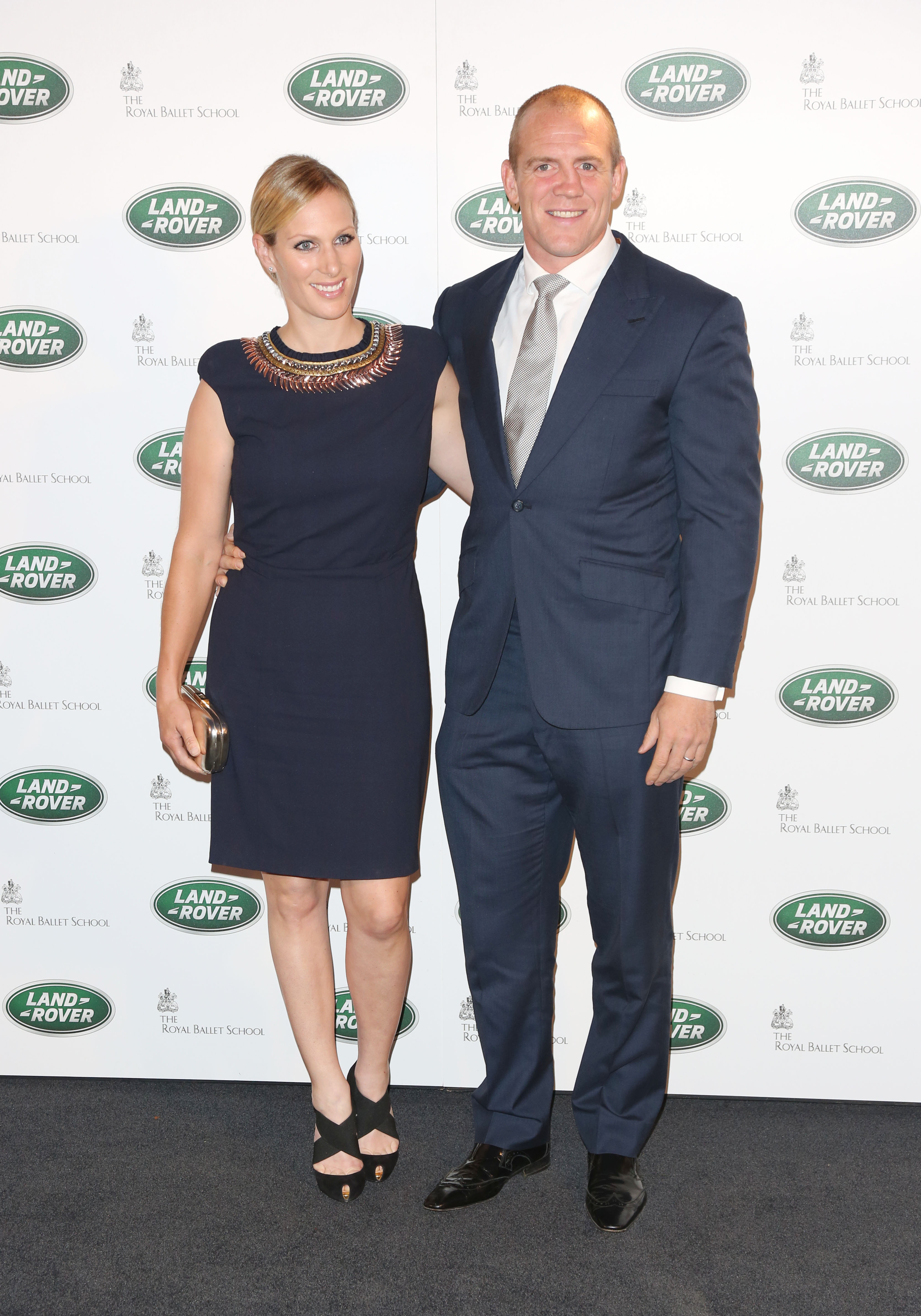 zara and mike tindall pose for a photograph together with land rover advertising background