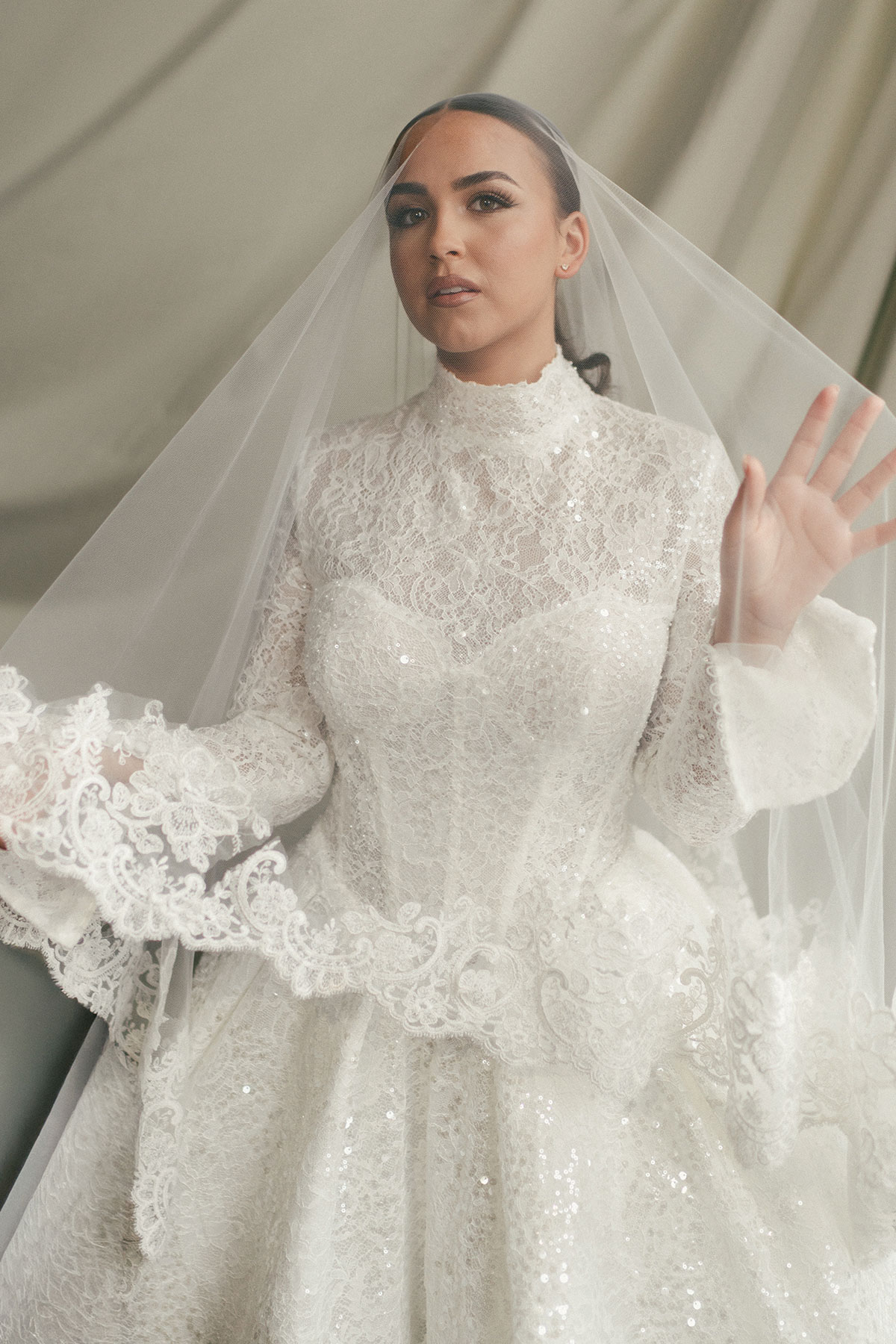 Bride wearing long-sleeve lace wedding dress with high neckline and veil, modern Scottish bridal fashion inspiration