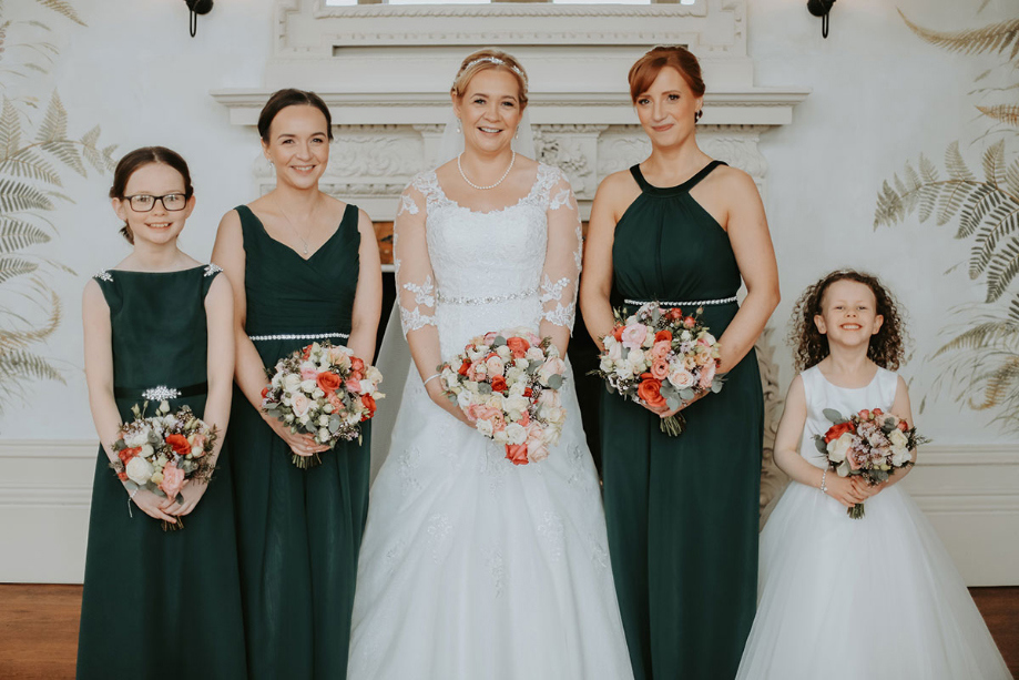 Bride and her bridesmaids who are wearing green dresses and flower girl in white gown