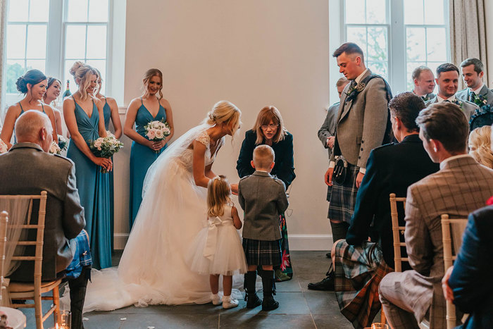 A little boy and a little girl standing next to a bride and groom during a wedding ceremony 