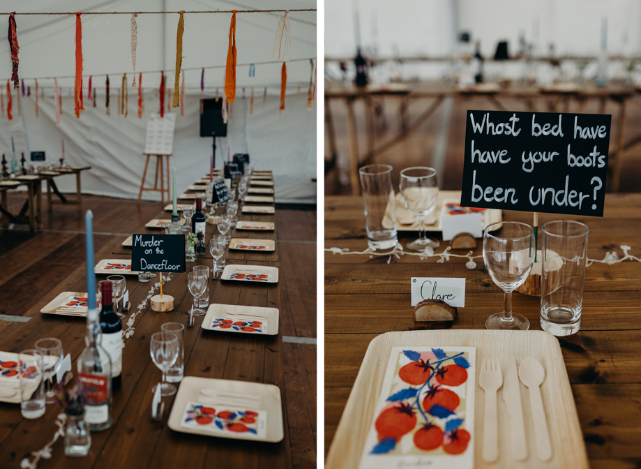 details of a table setting in a marquee featuring graphic red and blue tomato napkins, square wooden plates and cutlery. There is a wine glass and tall tumbler at each place setting and streamers in the background handing from the ceiling of a marquee