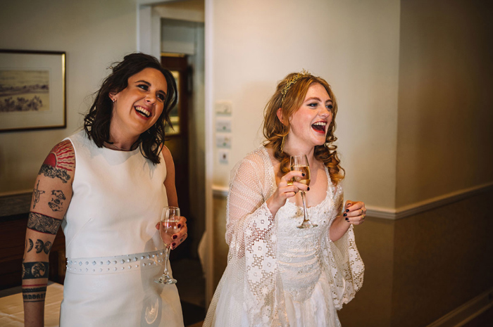 Two Brides Laughing Holding Champagne Flutes
