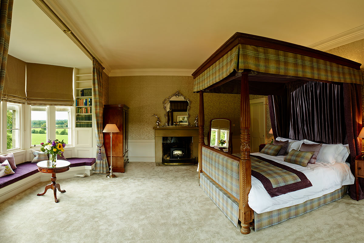 Luxury bedroom at Blairquhan Castle featuring a four-poster bed, fireplace, countryside views and traditional Scottish interiors