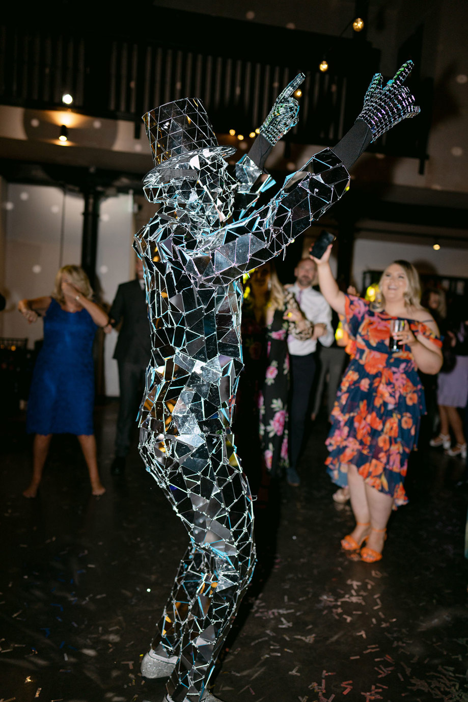 A person in mirror suit with people dancing in the background