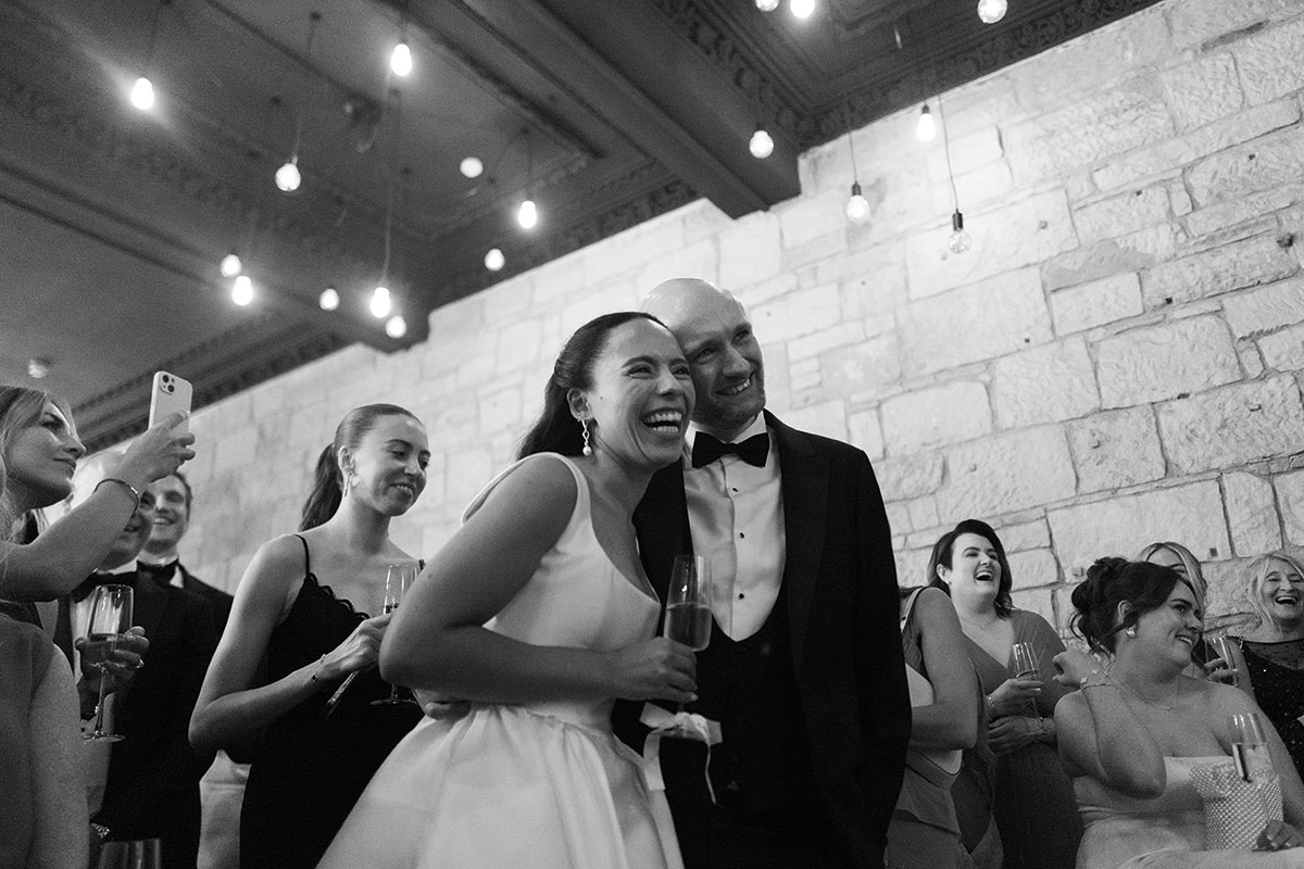 Bride and groom laughing with guests during Glasgow wedding reception at The Haberdashery under festoon lighting
