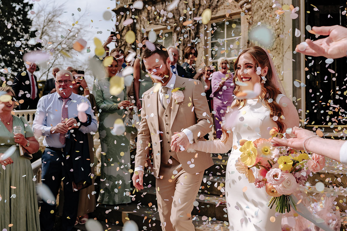 a bride and groom being showered in confetti outside Carlowrie Castle Edinburgh wedding venue