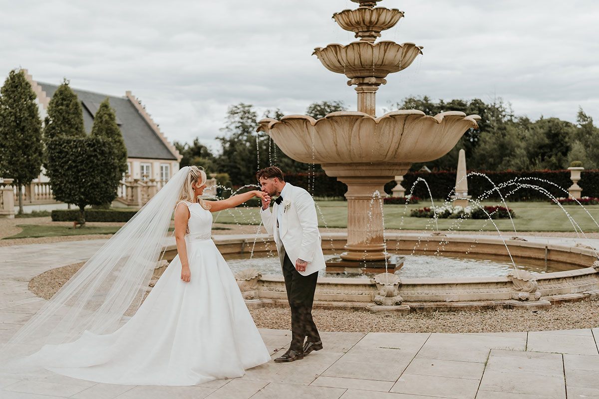 Bride and groom by fountain in landscaped gardens at Ingliston Country Club wedding