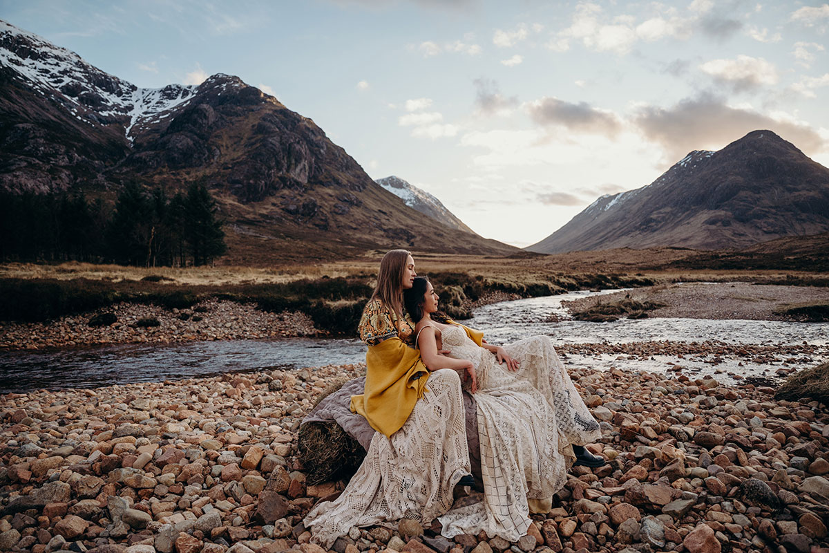 Couple sitting together by a river during a relaxed Scottish elopement shoot in Glencoe.