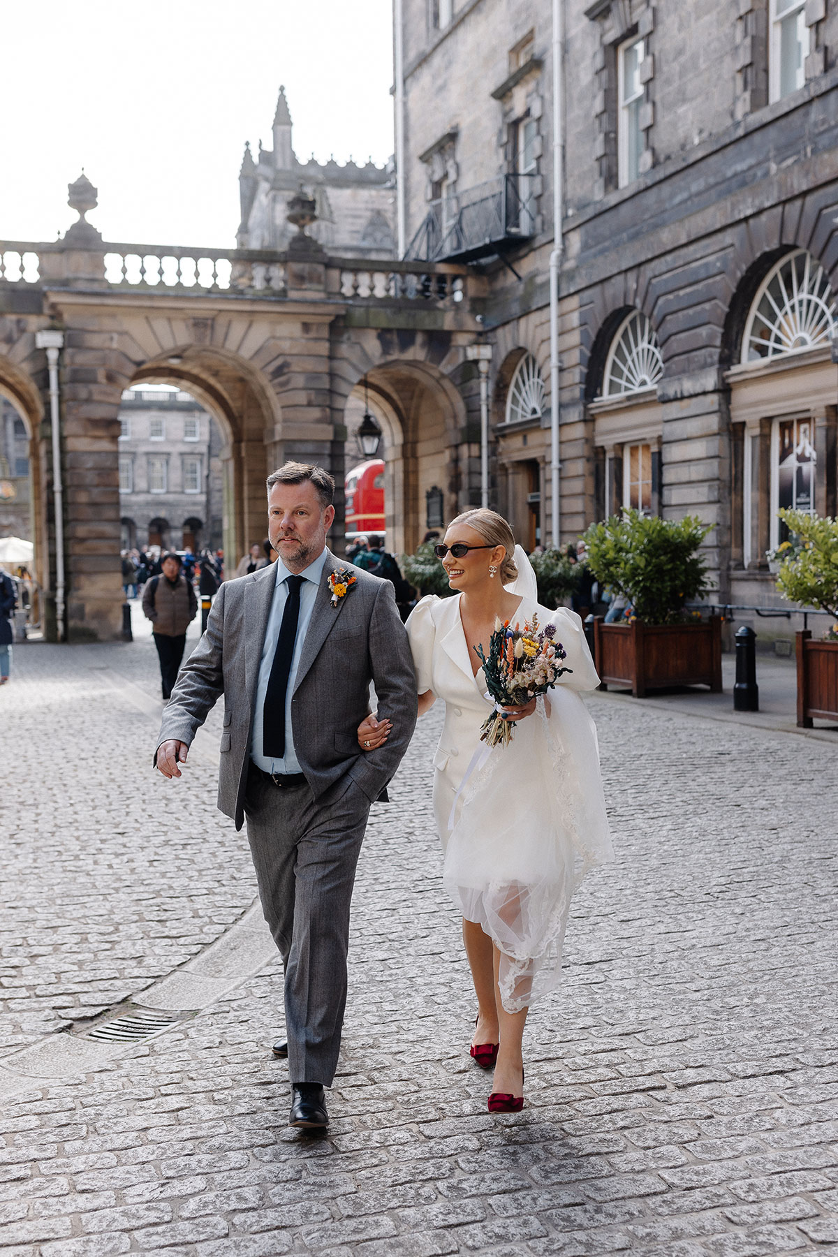 Bride walks arm-in-arm with her father through the courtyard at Edinburgh City Chambers before the registry office wedding ceremony.