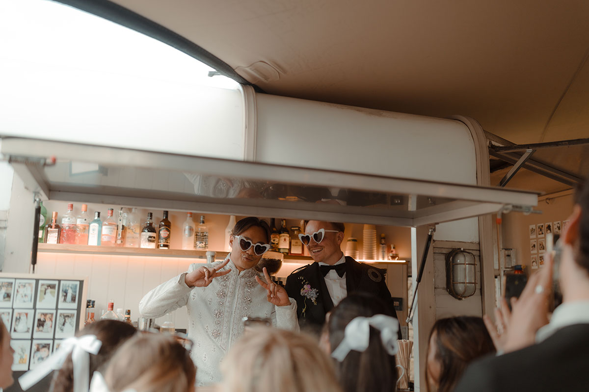 Newlywed grooms serving drinks from converted horsebox bar at their Falkirk farm wedding reception
