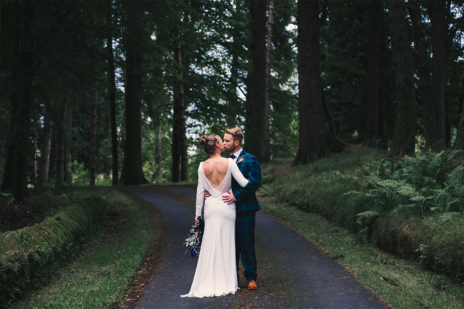 A bride and groom kissing in a forest