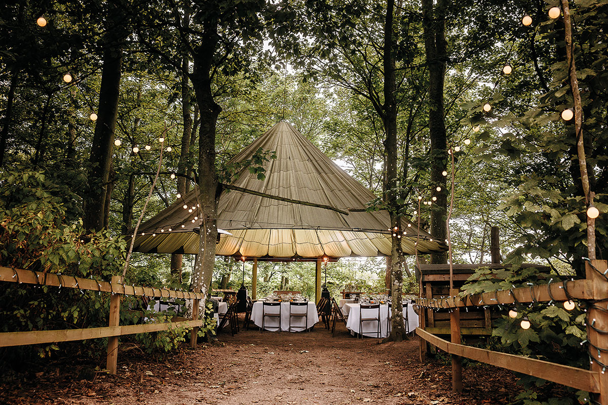 Cambo Estate Party Woodland tent set for outdoor wedding dining with festoon lighting in Fife