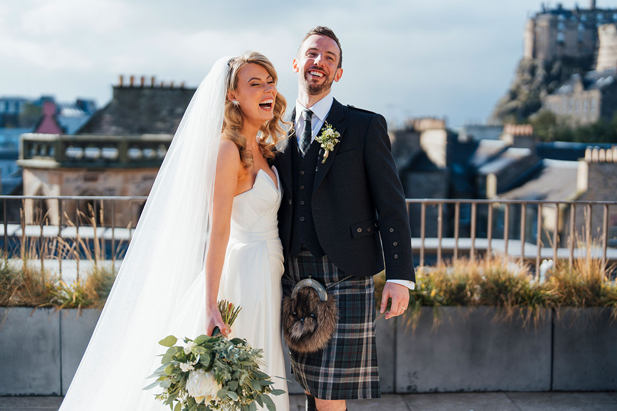 couple laughing outdoors with edinburgh castle in the background