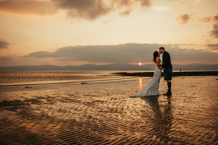 bride and groom kiss on the beach as the sun goes down during wedding at dougarie boathouse