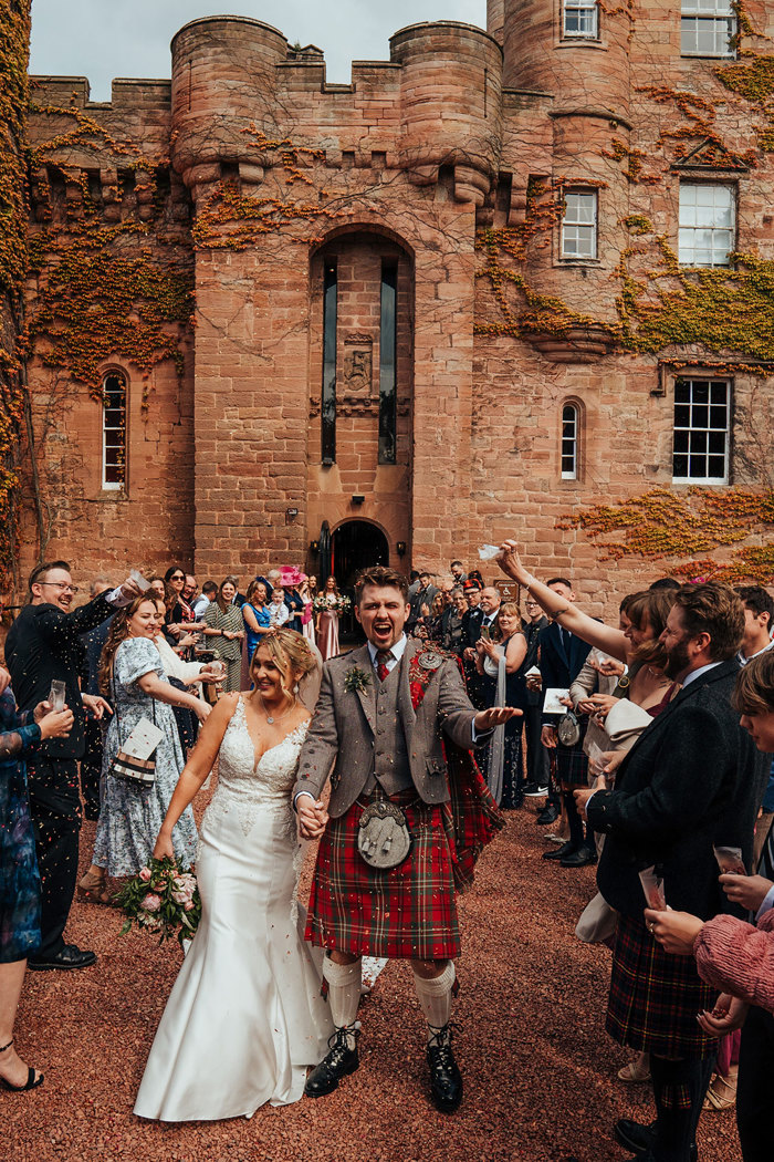 wedding guests cheer on bride and groom after wedding ceremony at dalhousie castle