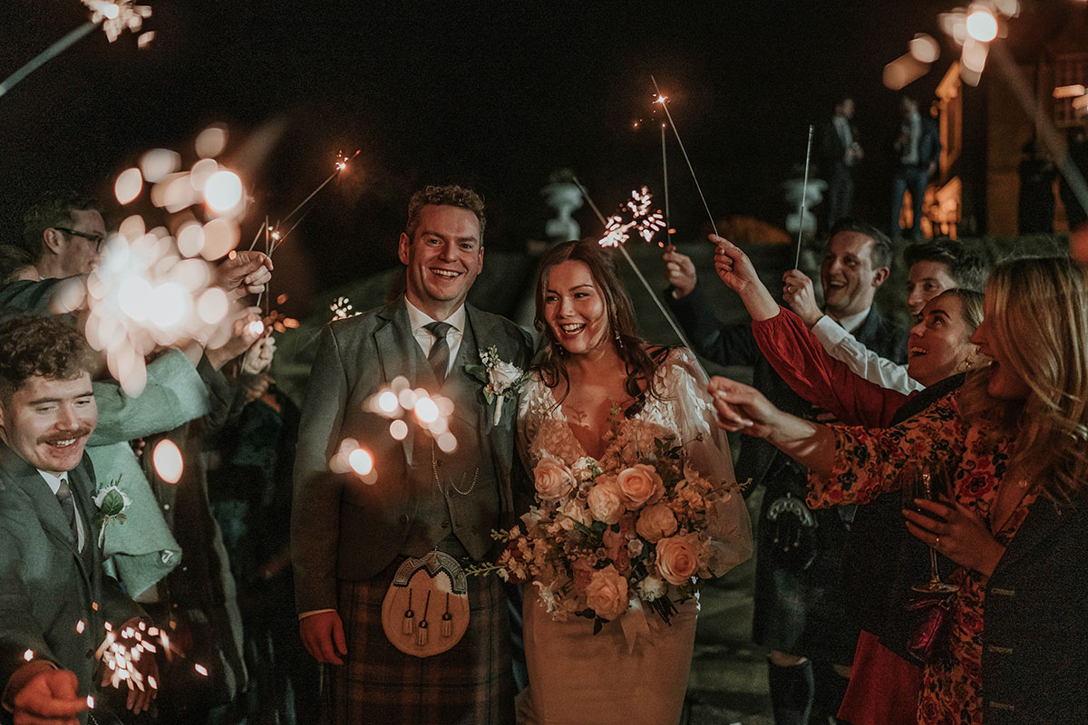 Evening sparklers with the bride and groom surrounded by guests.