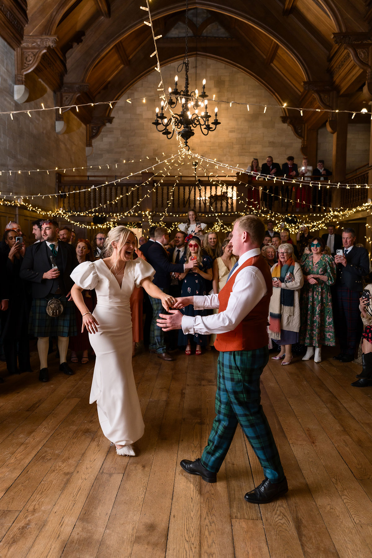 bride and groom smile on the dancefloor with guests during wedding reception at achnagairn castle