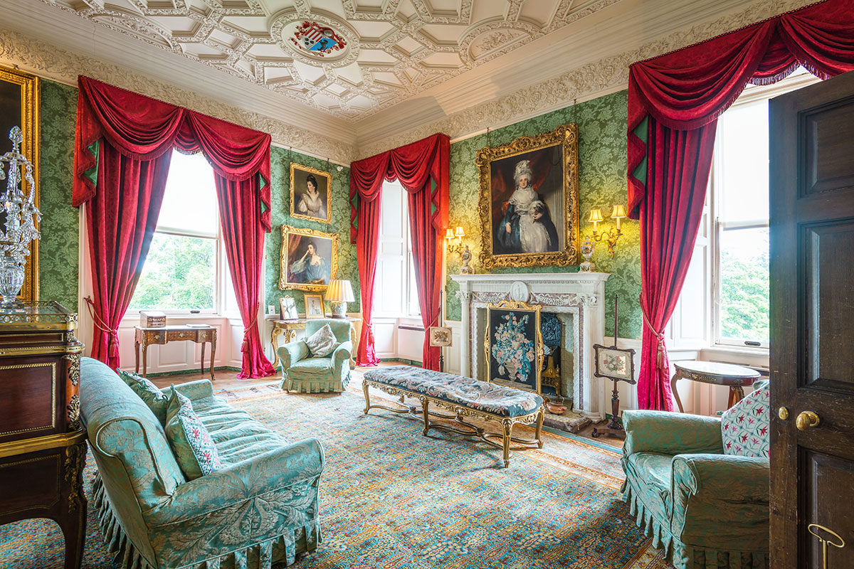 Elegant drawing room at Fyvie Castle with ornate plasterwork, period furnishings, grand fireplace and rich red draped windows