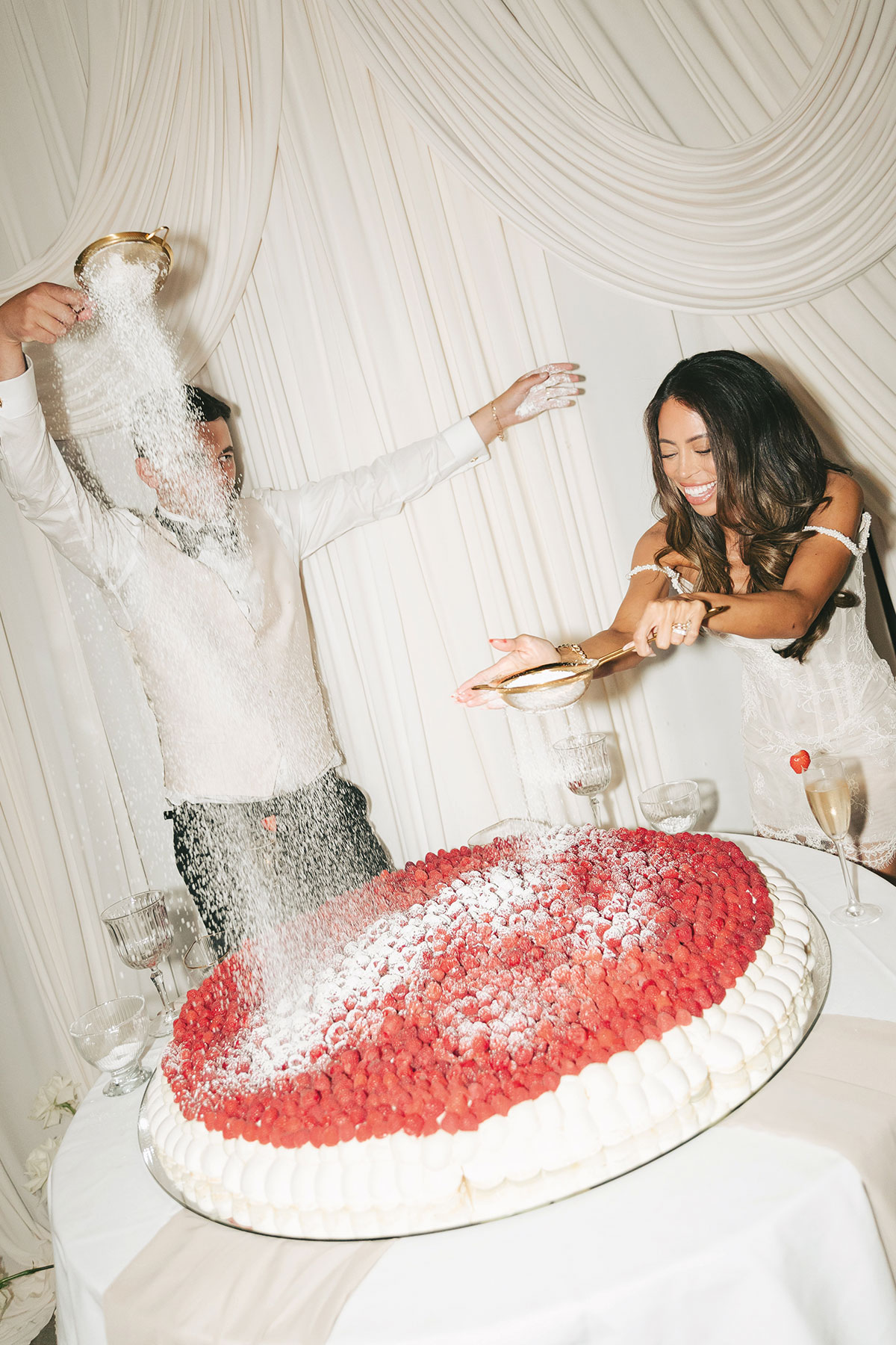 Newlyweds adding icing sugar to a giant raspberry pavlova during their wedding reception in Glasgow.