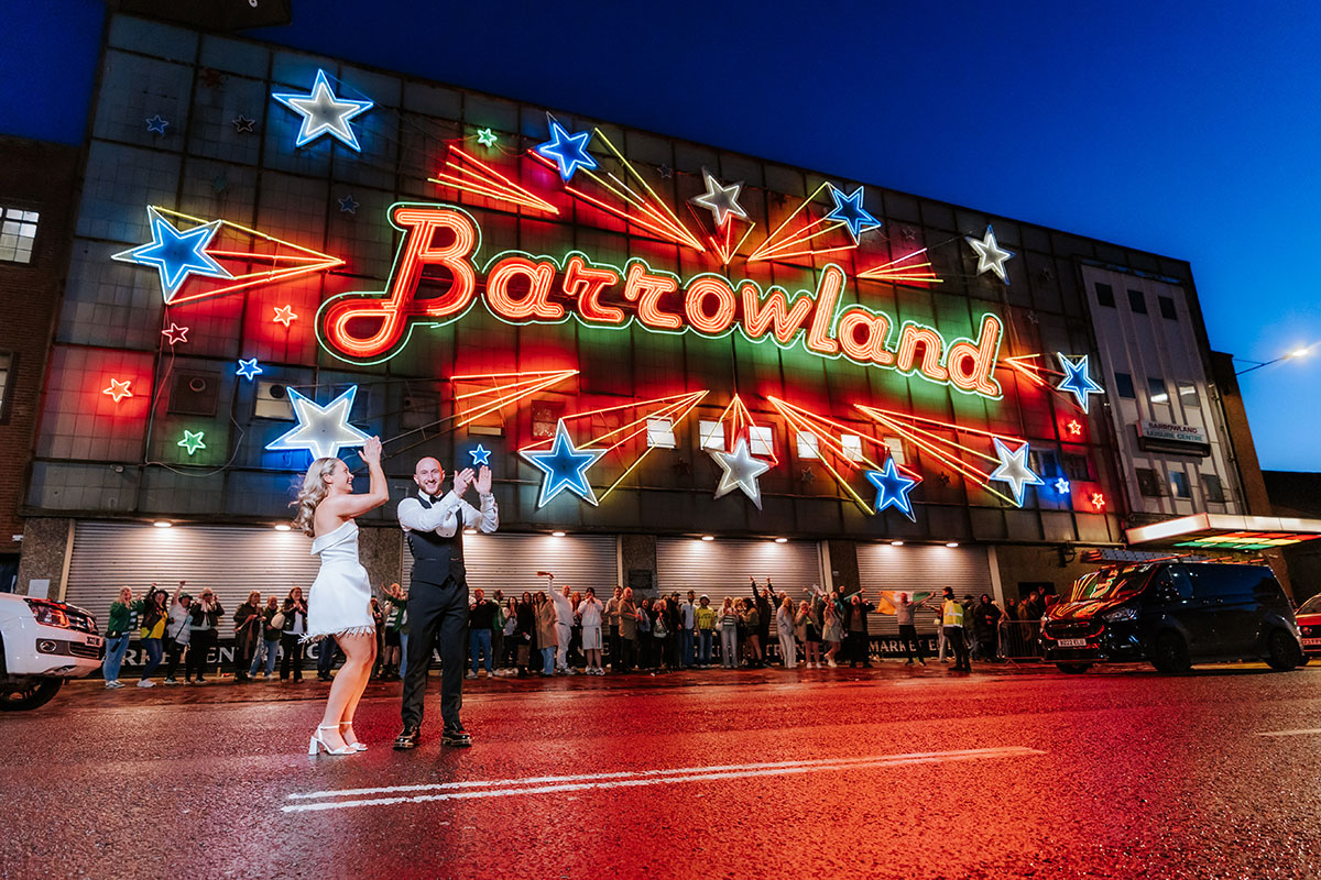 Newlyweds posing outside the illuminated Barrowland Ballroom sign near BAaD in Glasgow.