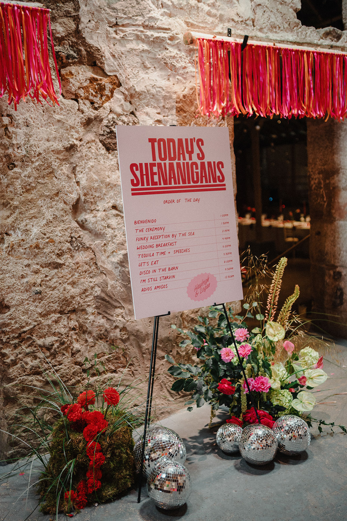 Red and pink order of the day sign on easel with colourful pink and red flowers and disco ballls.
