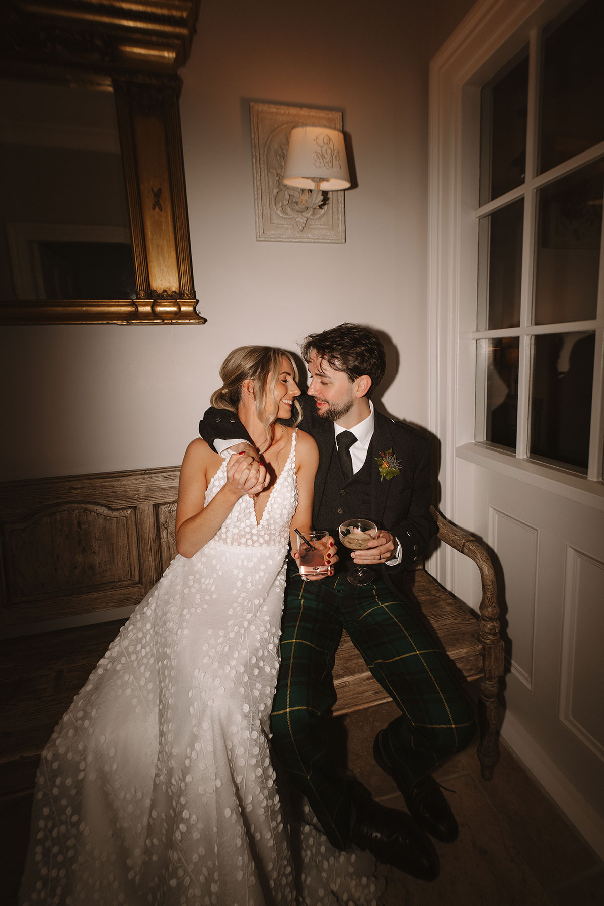 Flash photograph of the bride and groom holding cocktails and looking at one another