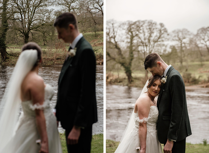 A bride and groom stand close together outside in front of a river