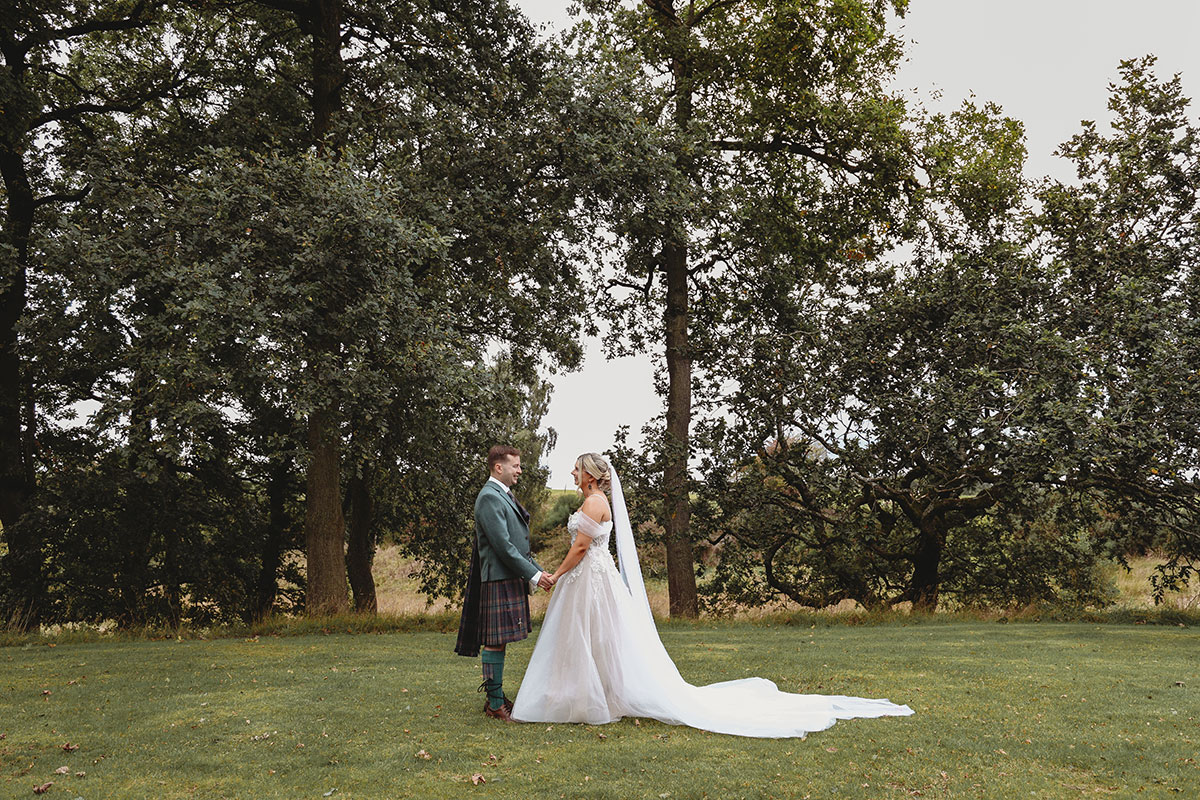 Bride and groom holding hands during portraits in the grounds of a Scottish woodland wedding venue