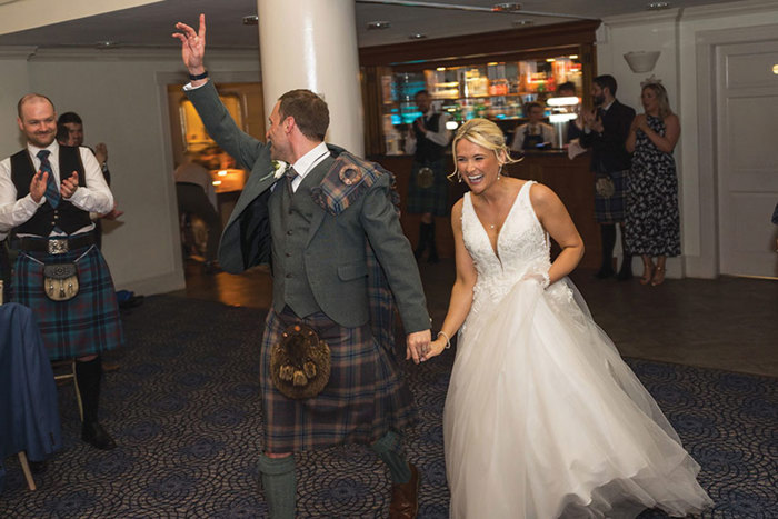 bride and groom run into their wedding reception ready to celebrate