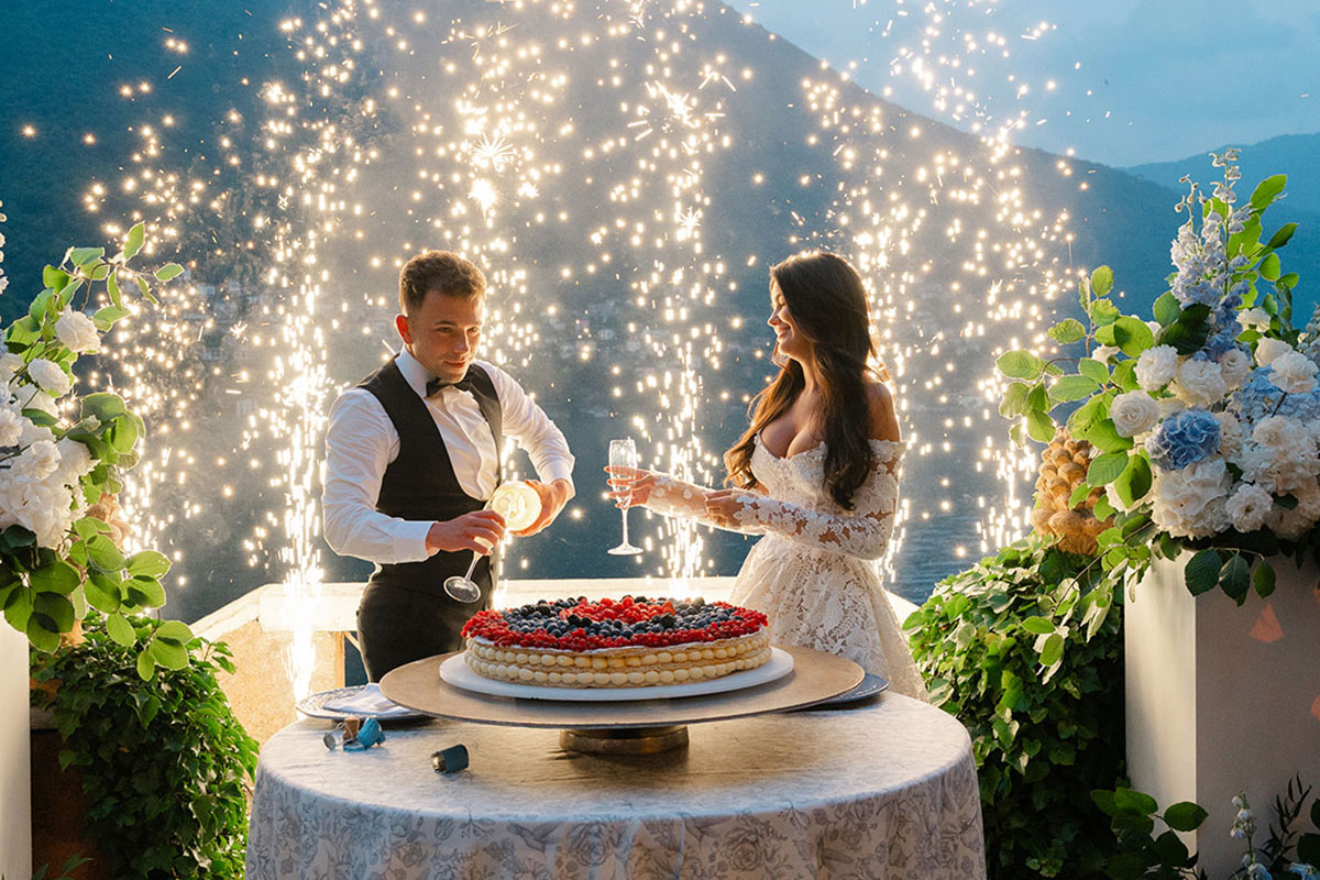 Bride and groom cutting a millefoglie wedding cake as pyrotechnic sparklers light up the Lake Como evening.