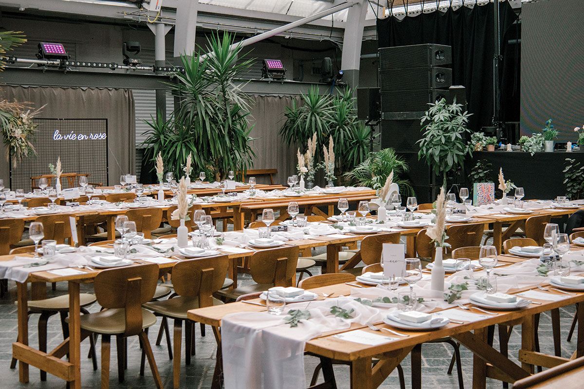 Wedding reception setup with long tables, greenery and neon signage inside BAaD Glasgow industrial venue