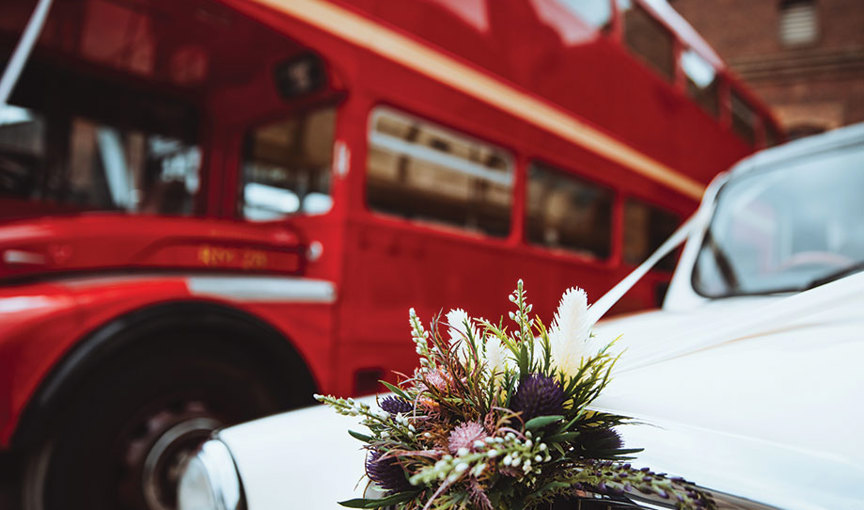 a bouquet of flowers on the bonnet of a white car with red Routemaster bus in background
