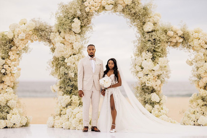 Simone Biles and Jonathan Owens surrounded by white roses during their wedding