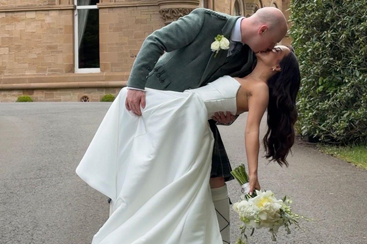 Newlywed couple kissing by a castle